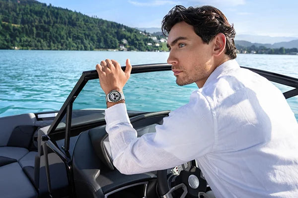 Mann am Steuer eines Motorbootes mit jacques lemans Uhr