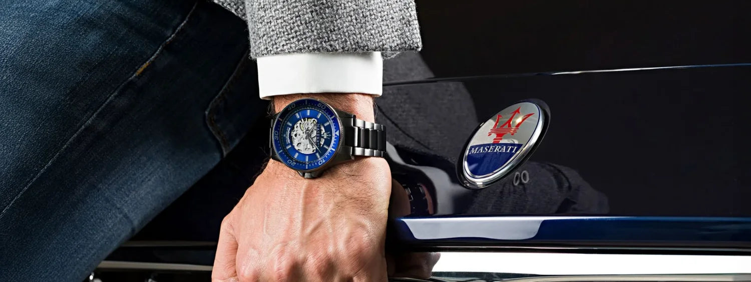 Hand eines Mannes auf der Kühlerhaube seines Maseratis mit einer Maserati Herrenuhr