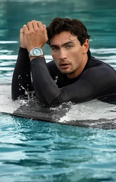 Man im Wasser auf Surfboard mit Jacques Lemans Uhr